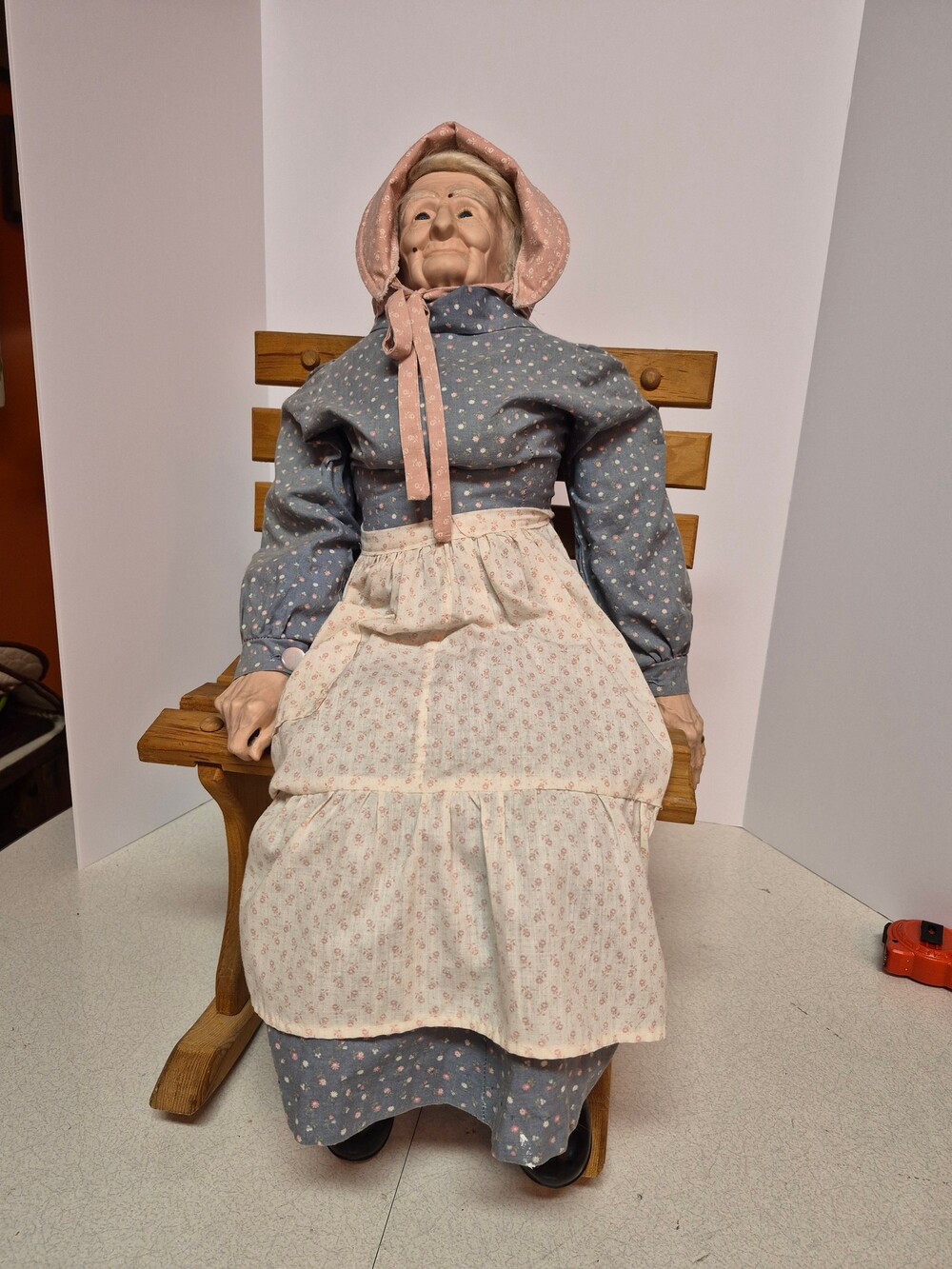 Vintage Wooden Doll in Blue Dress with Pink Bonnet and Apron on Rocking Chair